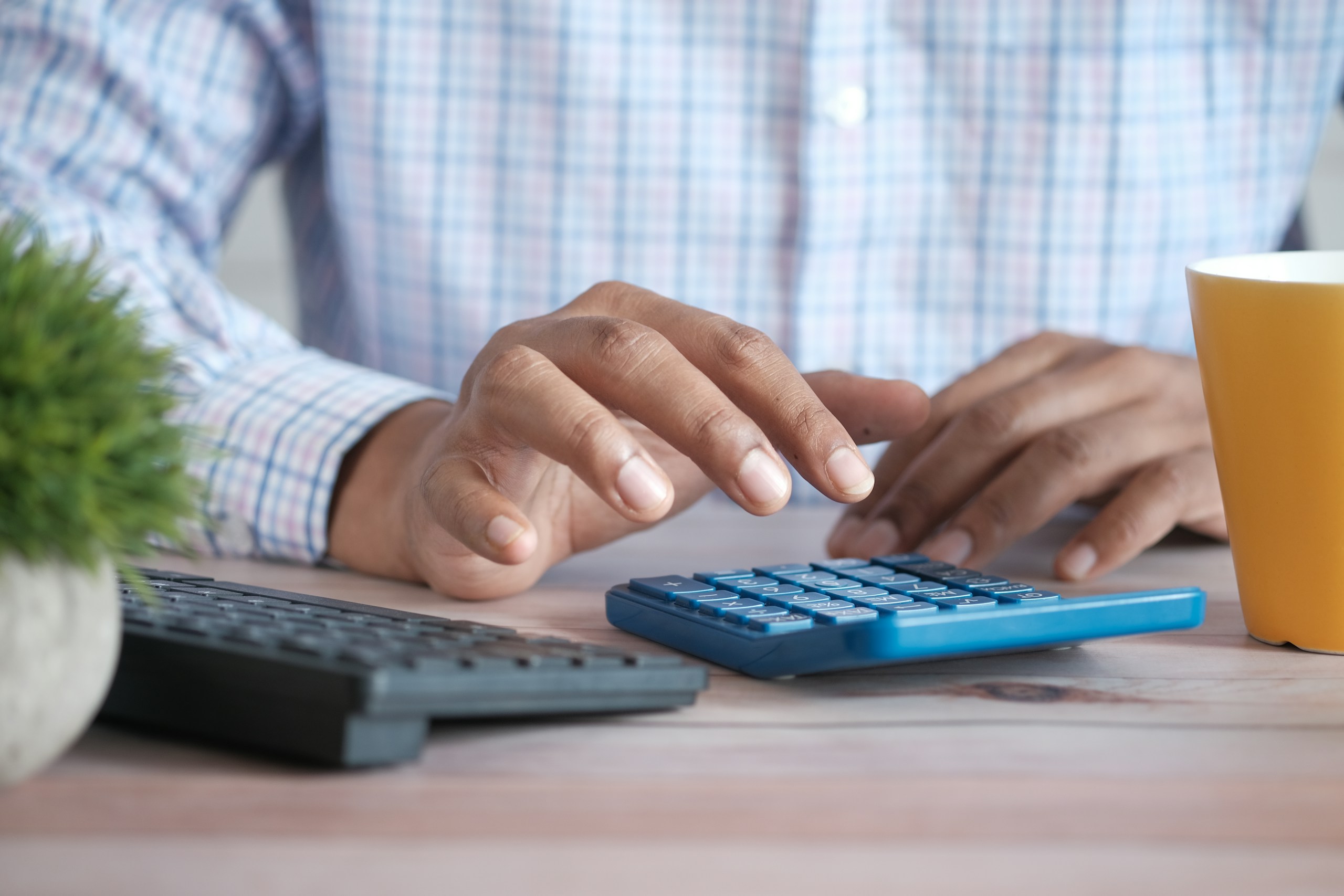 Close up of man hand using calculator.