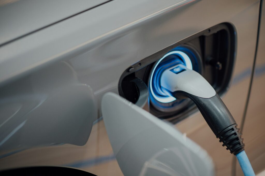 Close-up of a car charging port with a blue charging connector plugged in.