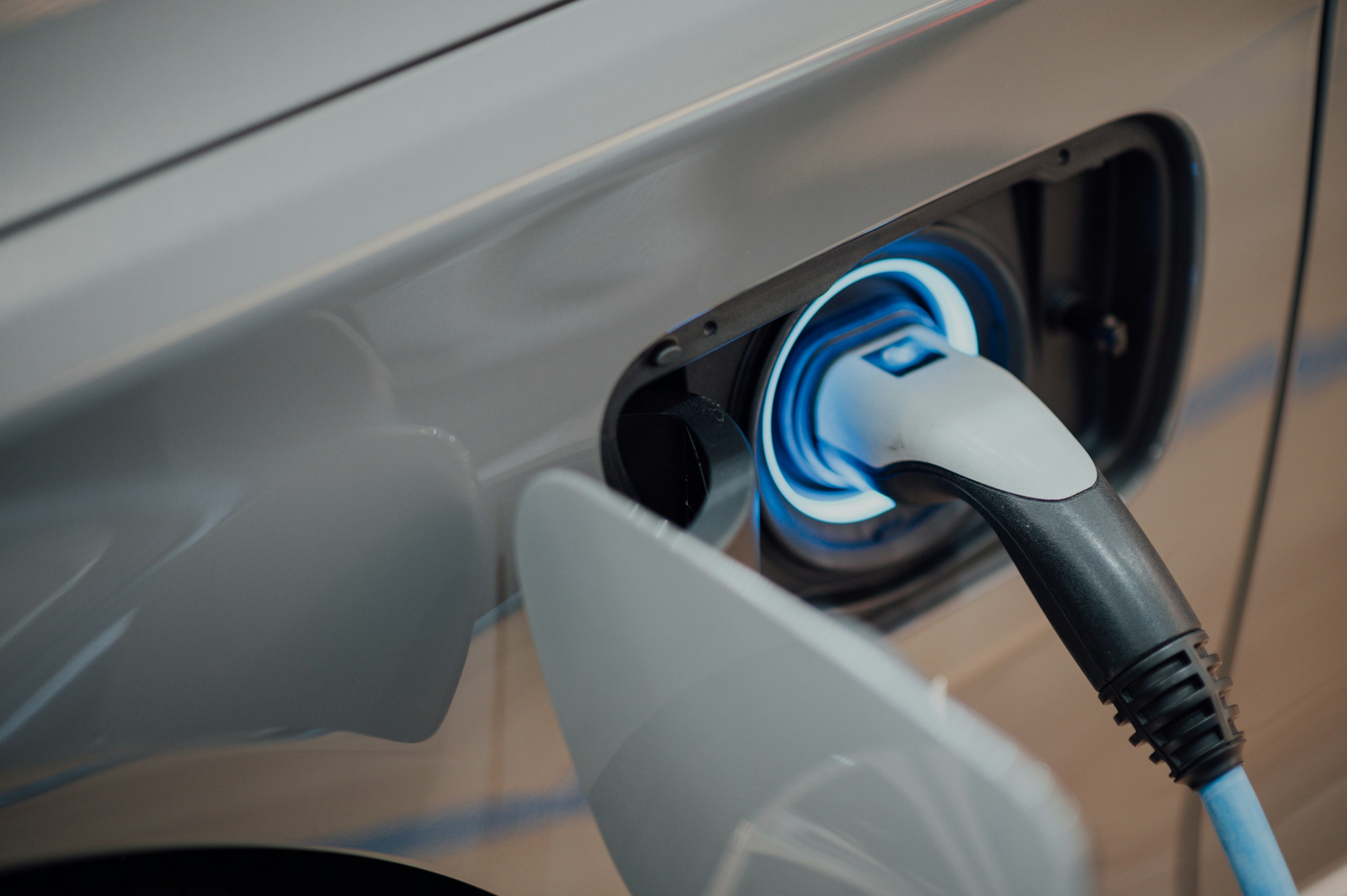 Close-up of a car charging port with a blue charging connector plugged in.