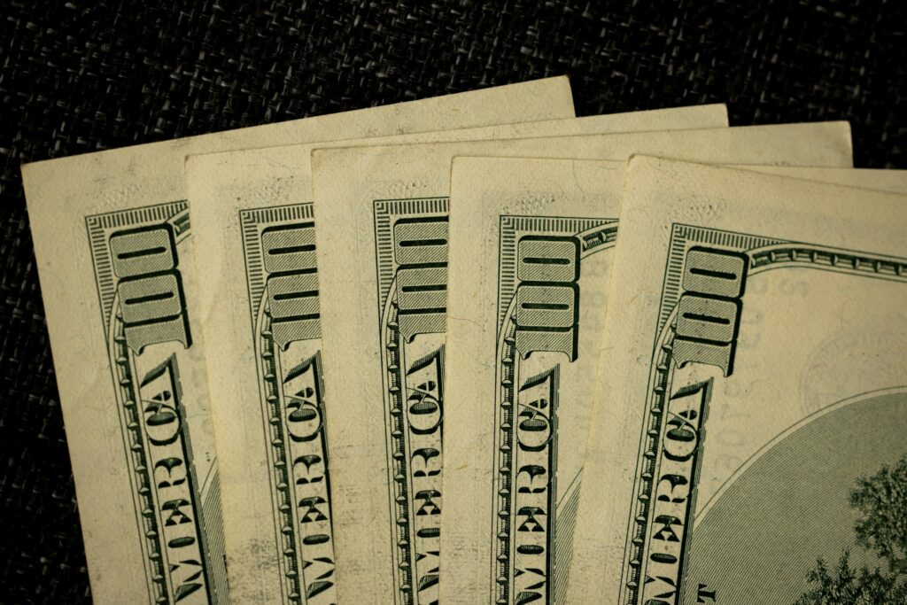 Fanned stack of US $100 bills on a dark textured background