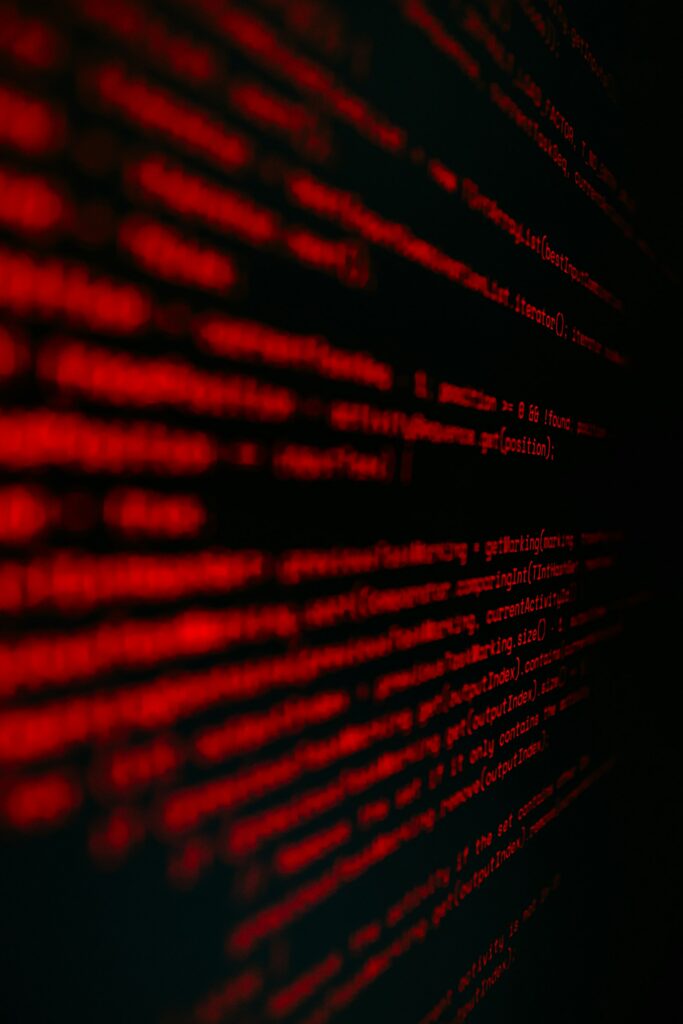 Red programming code on a dark background, close-up perspective of scrolling lines.