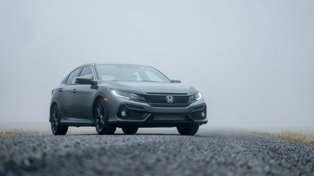 Gray Honda sedan angled from the front-left on a foggy road with dim light.