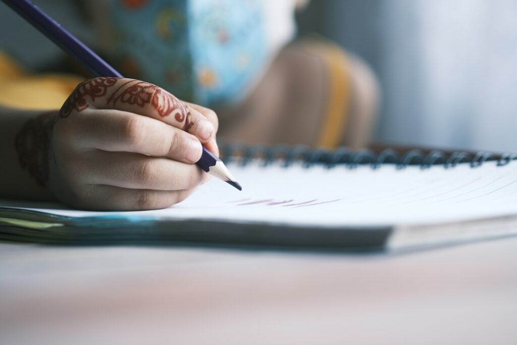 child girl in face mask hand writing on notepad.
