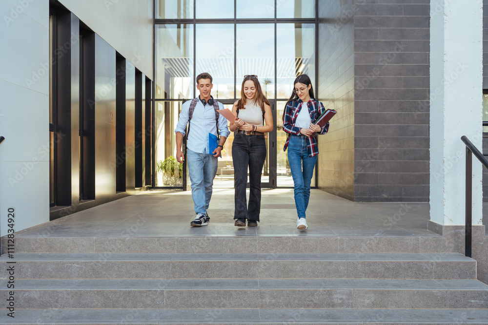 Happy college classmates with notebooks walking downstairs