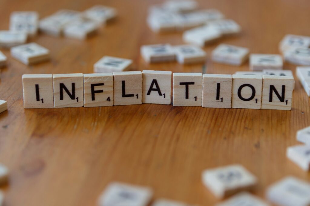 Scrabble tiles spell 'INFLATION' on a wooden table.