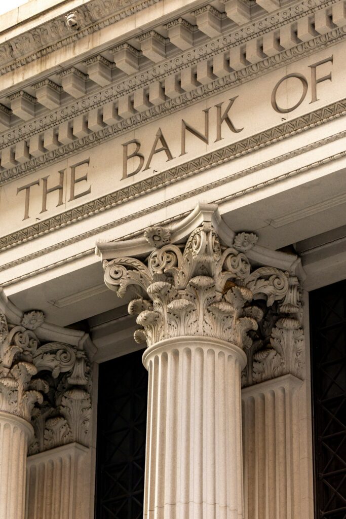 Close-up of a bank façade showing tall fluted columns with decorative Corinthian capitals and a detailed frieze above the entrance.