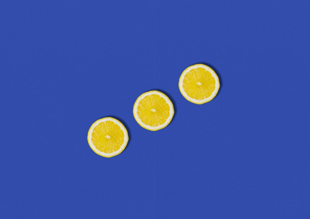 Five yellow lemon slices arranged diagonally on a vivid blue background for decorative contrast, forming a curved line across the bottom-right.
