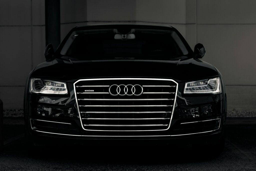 Front view of a black Audi SUV, chrome grille with the four-ring logo, headlights visible in low light.