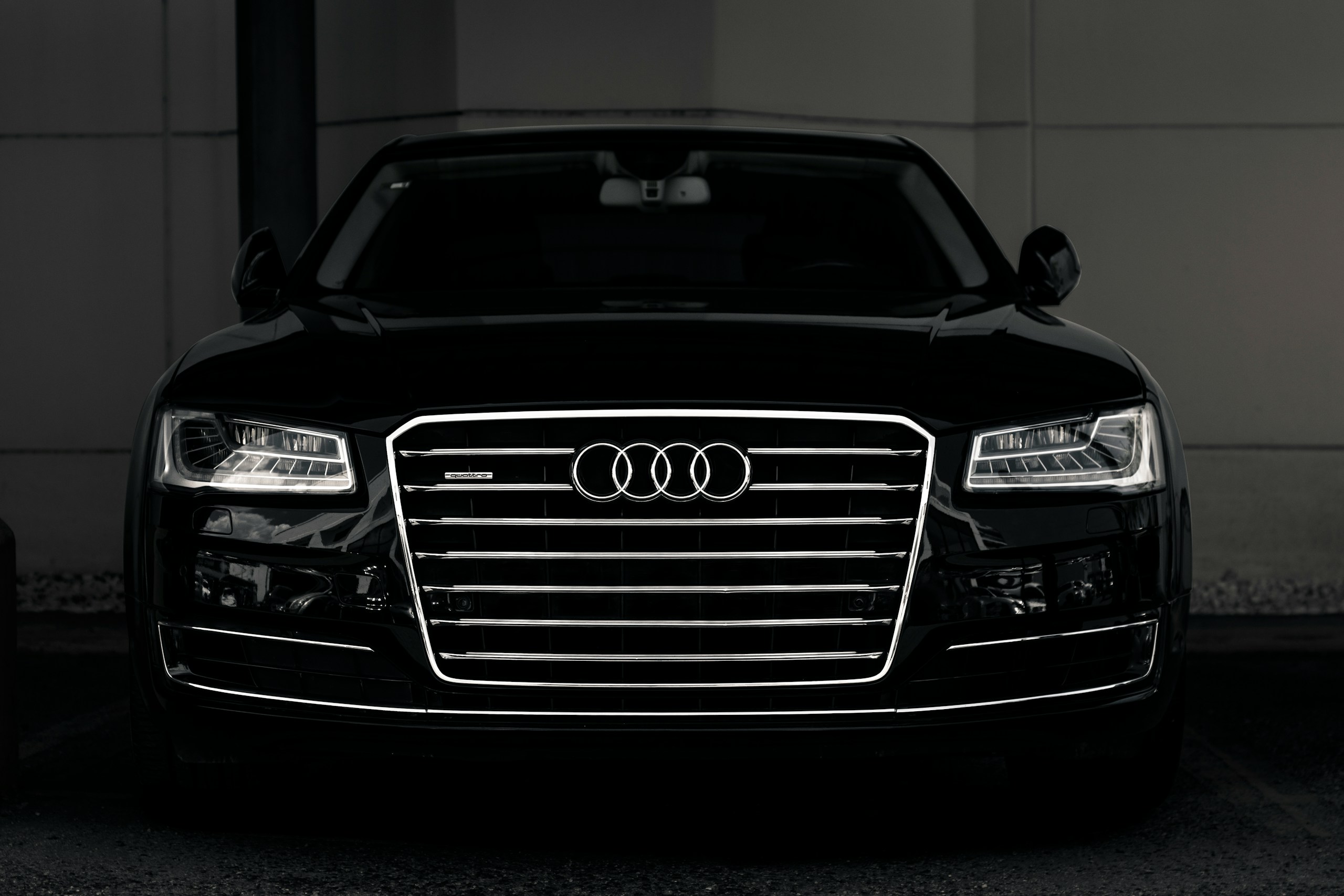 Front view of a black Audi SUV, chrome grille with the four-ring logo, headlights visible in low light.