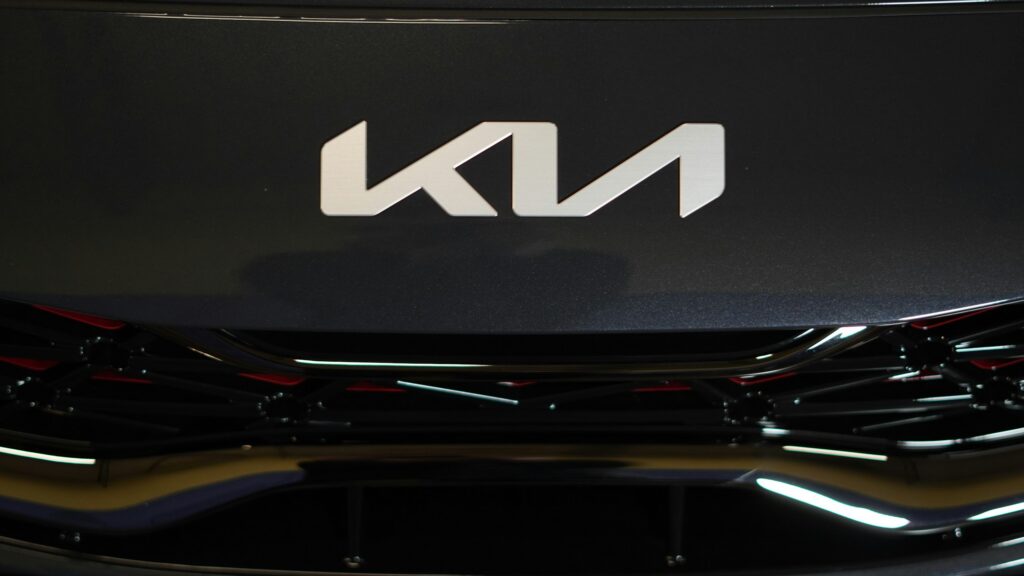 Close-up of a dark car hood with a large, silver, geometric emblem in the center.