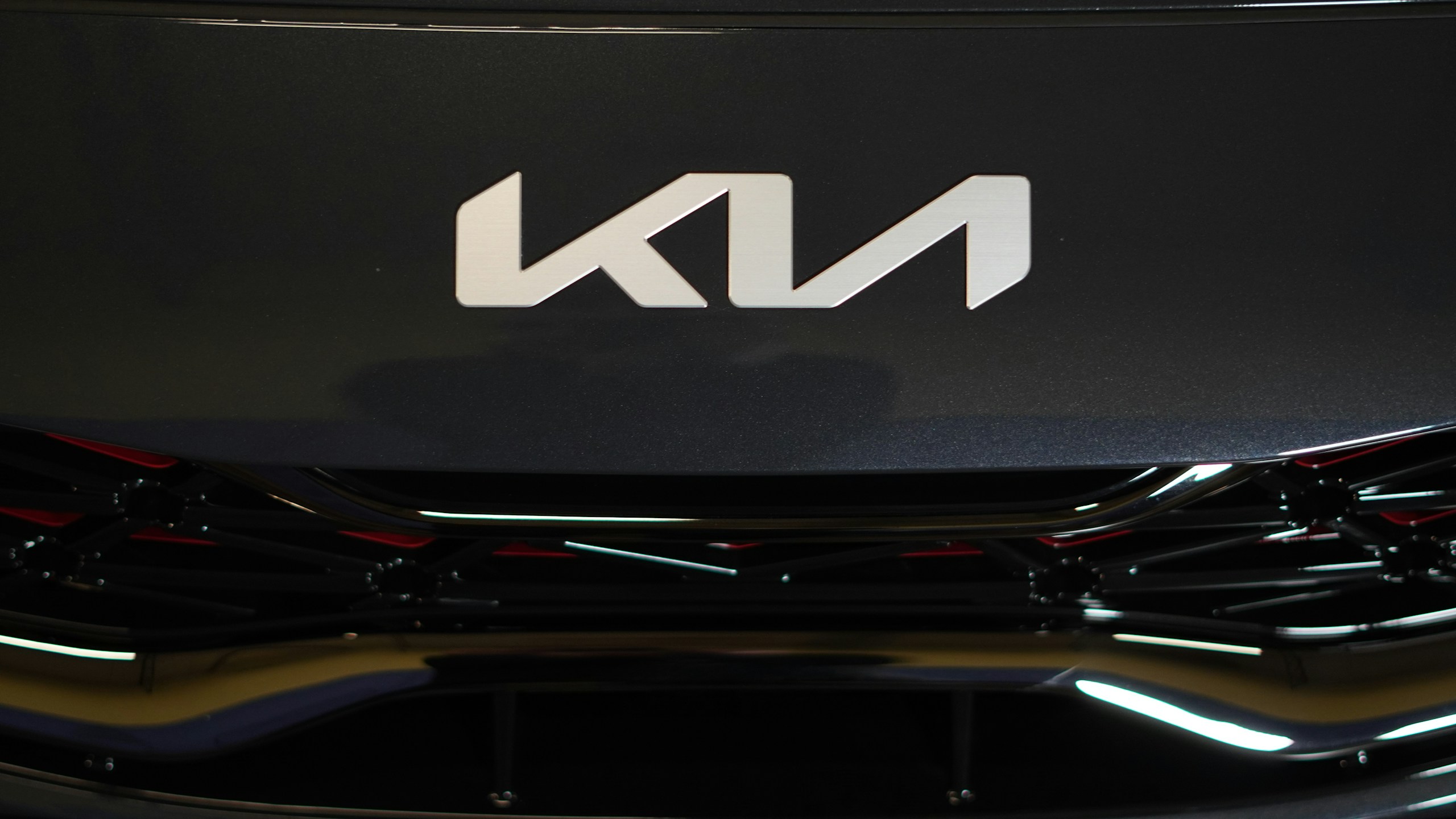 Close-up of a dark car hood with a large, silver, geometric emblem in the center.