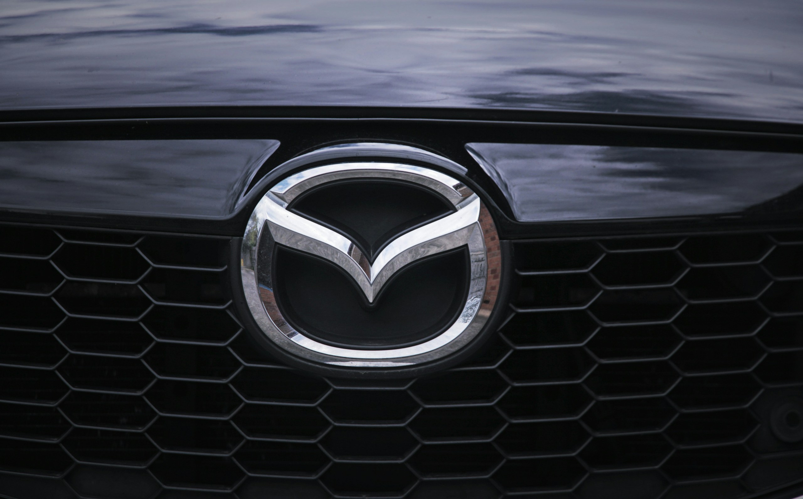 Close-up of a car's front grille featuring a silver Mazda emblem.