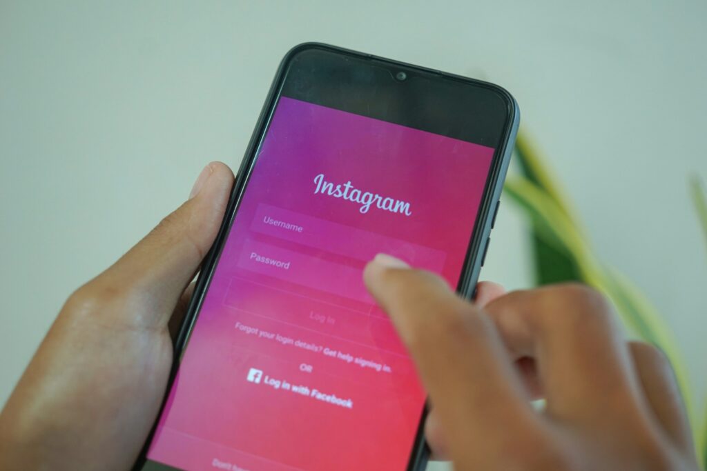 Hand holding a smartphone showing the Instagram login screen with Username and Password fields partially visible