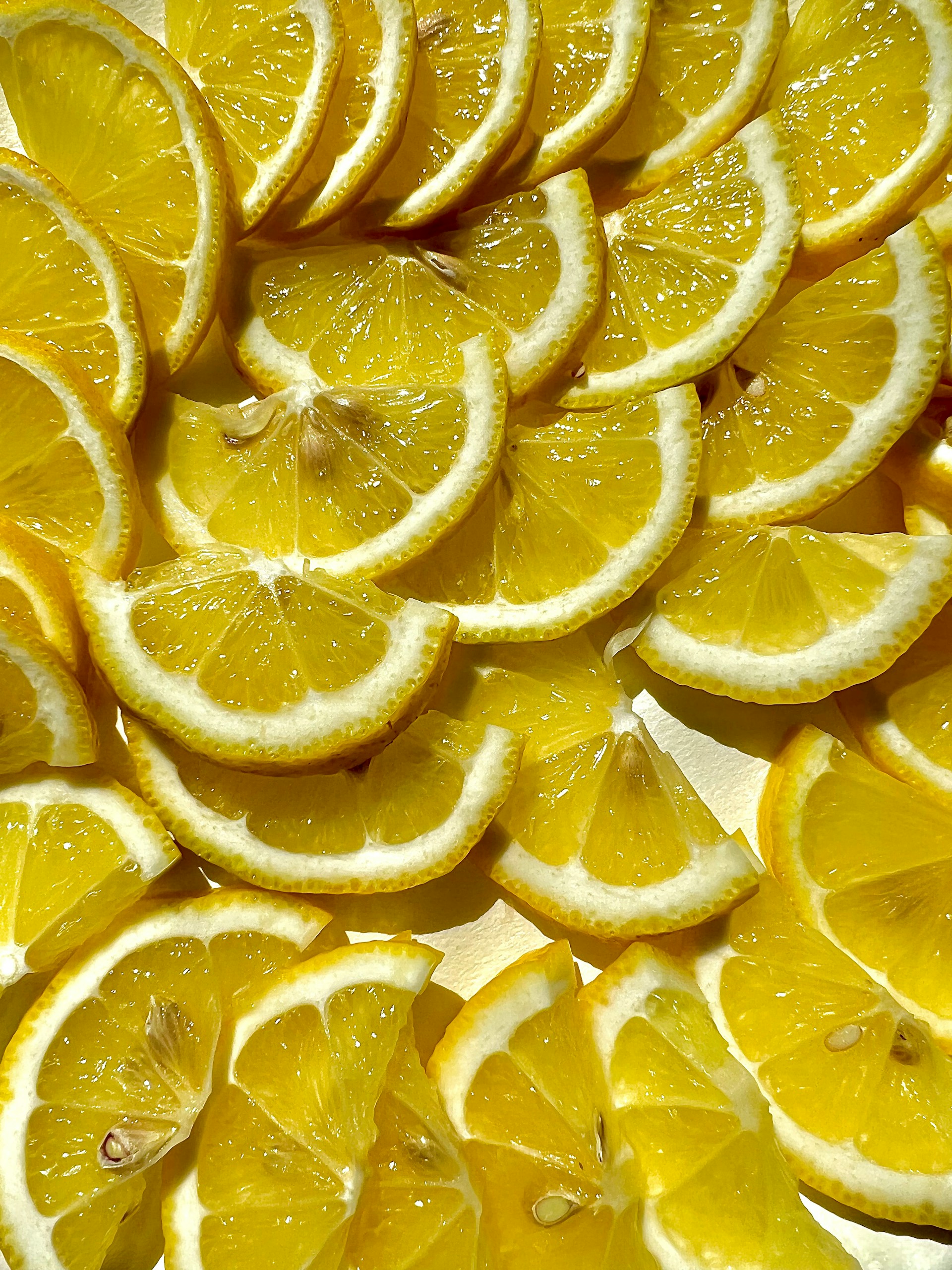 Close-up of many orange slices arranged together showing bright yellow flesh and white rind edge, fresh and juicy feel.