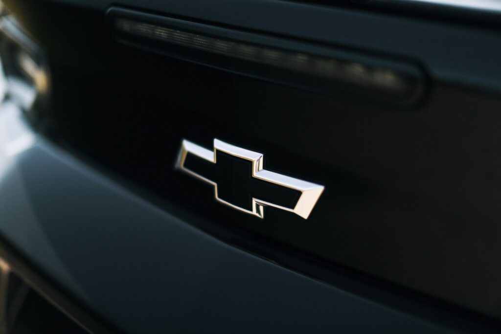 Close-up of a chrome car badge on a dark, glossy car surface.