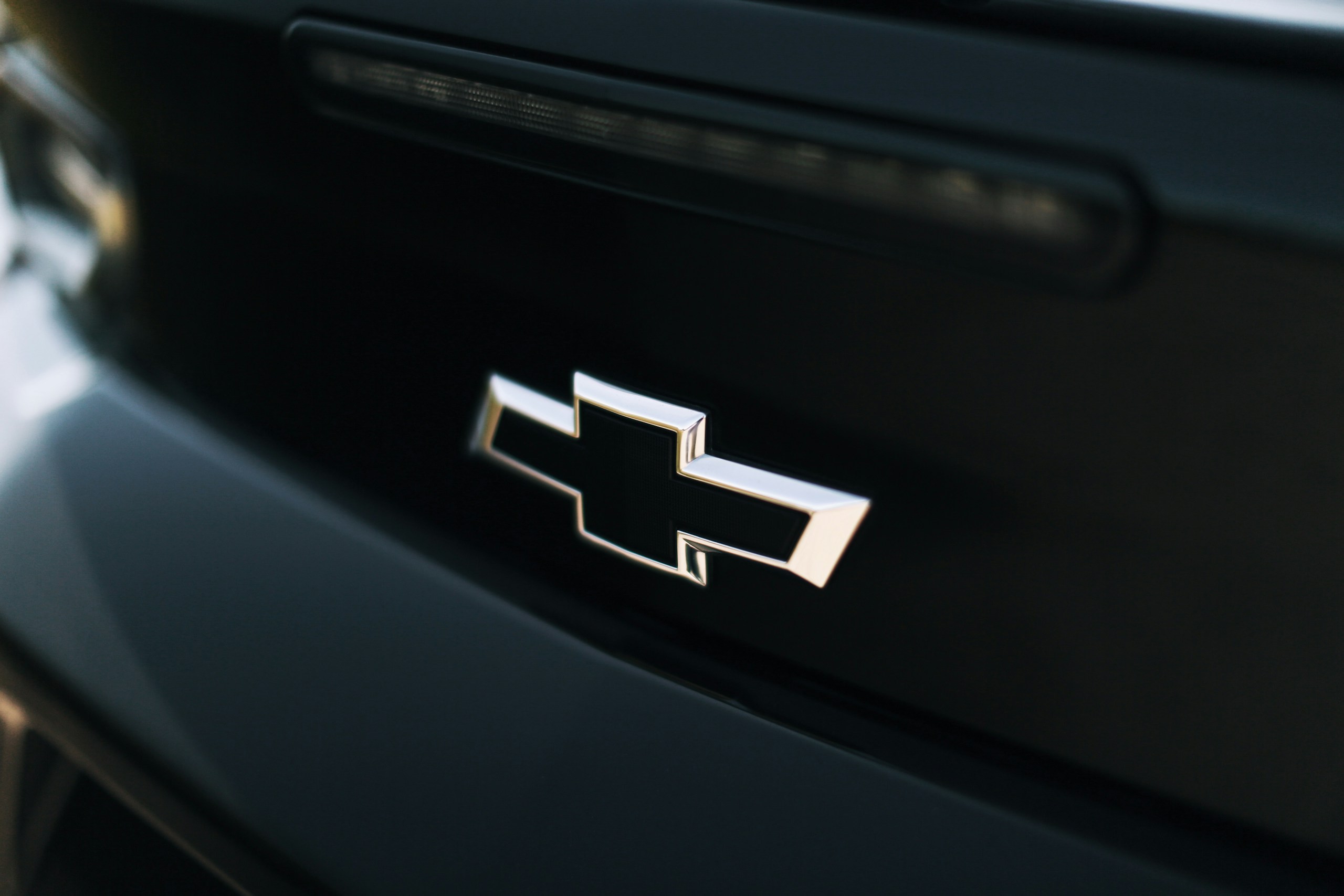 Close-up of a chrome car badge on a dark, glossy car surface.
