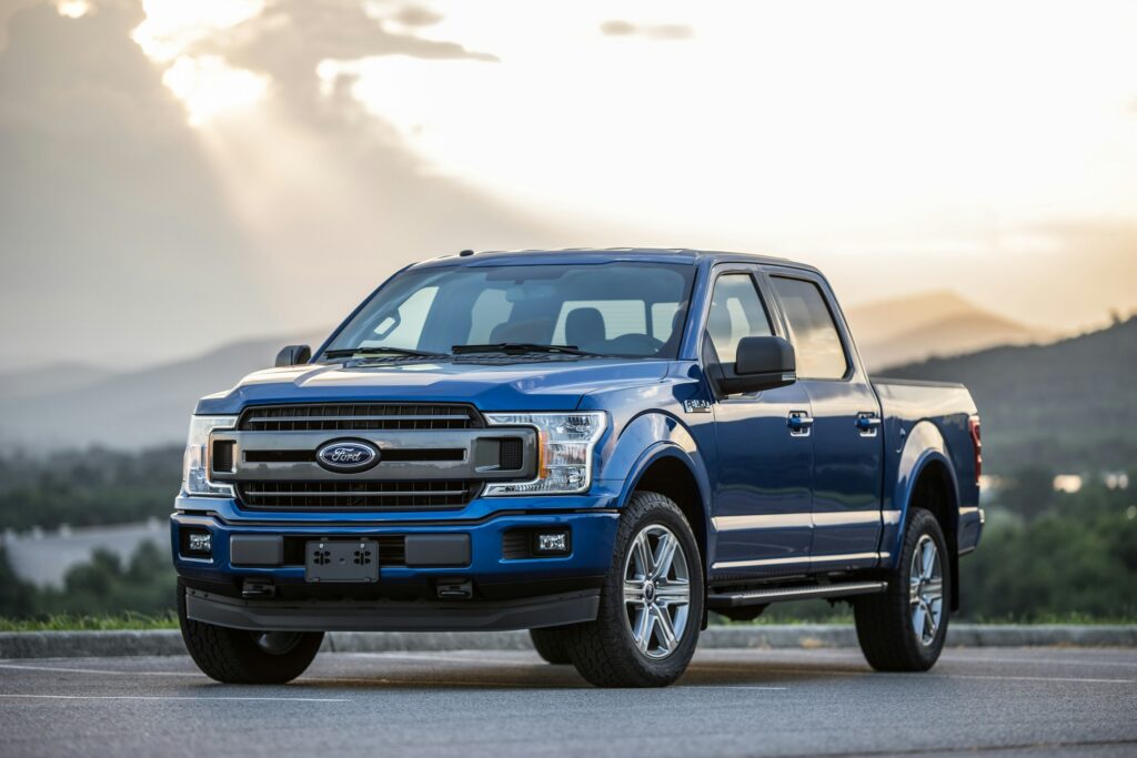 Blue Ford pickup truck parked on a road with hills in the background at sunset/early evening
