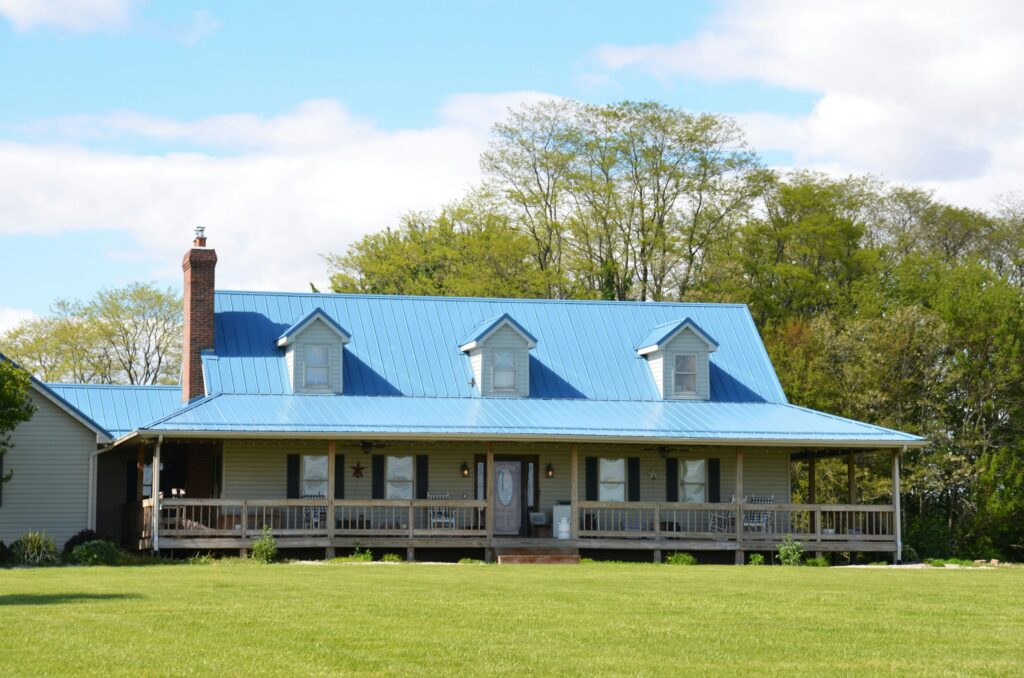 Blue roofed Farmhouse with long front porch with dormers