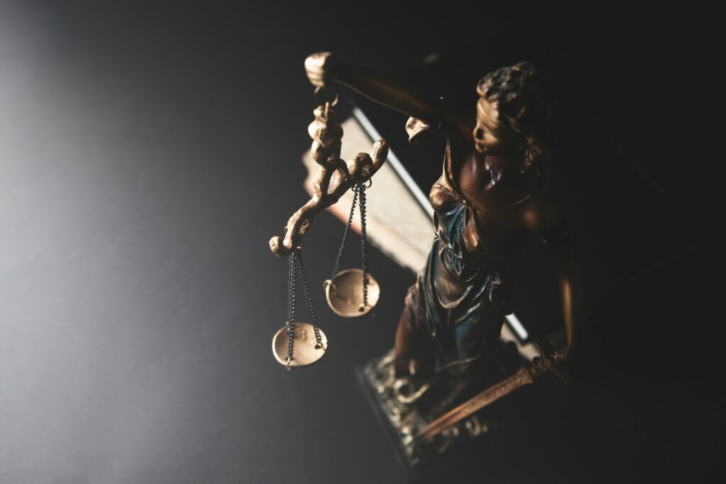 Statue of justice and scales of justice on a black background.